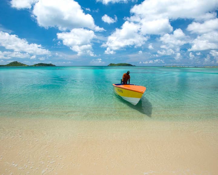 A man with a yellow boat at Paradise beach in Carriacou.