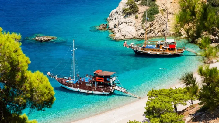 Sailboats beached in Karpathos in beautiful clear waters next to cliffs